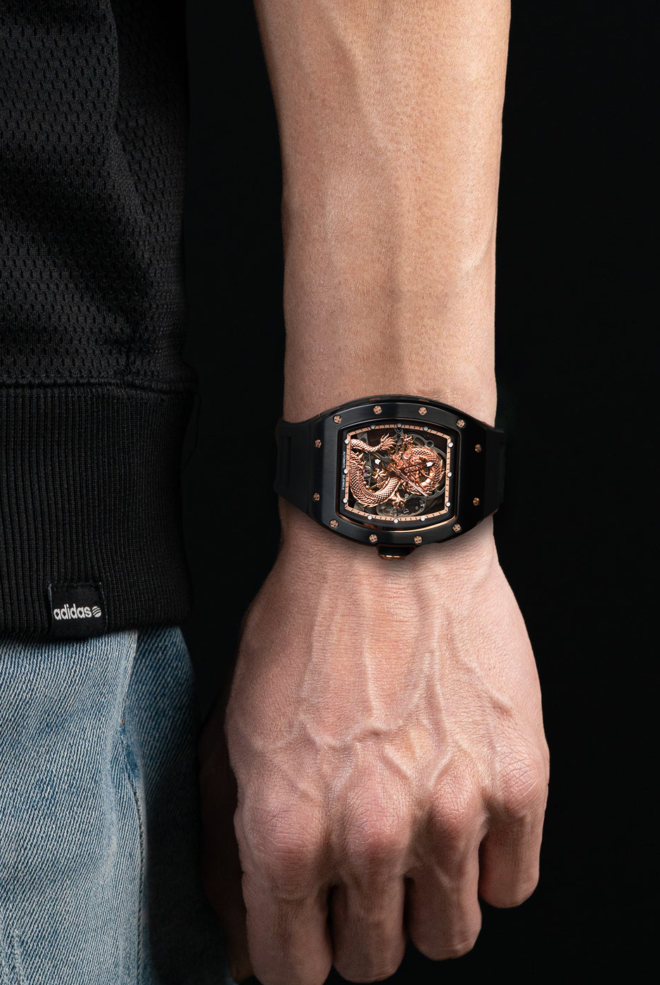 Person wearing a black watch with a detailed face on a black background