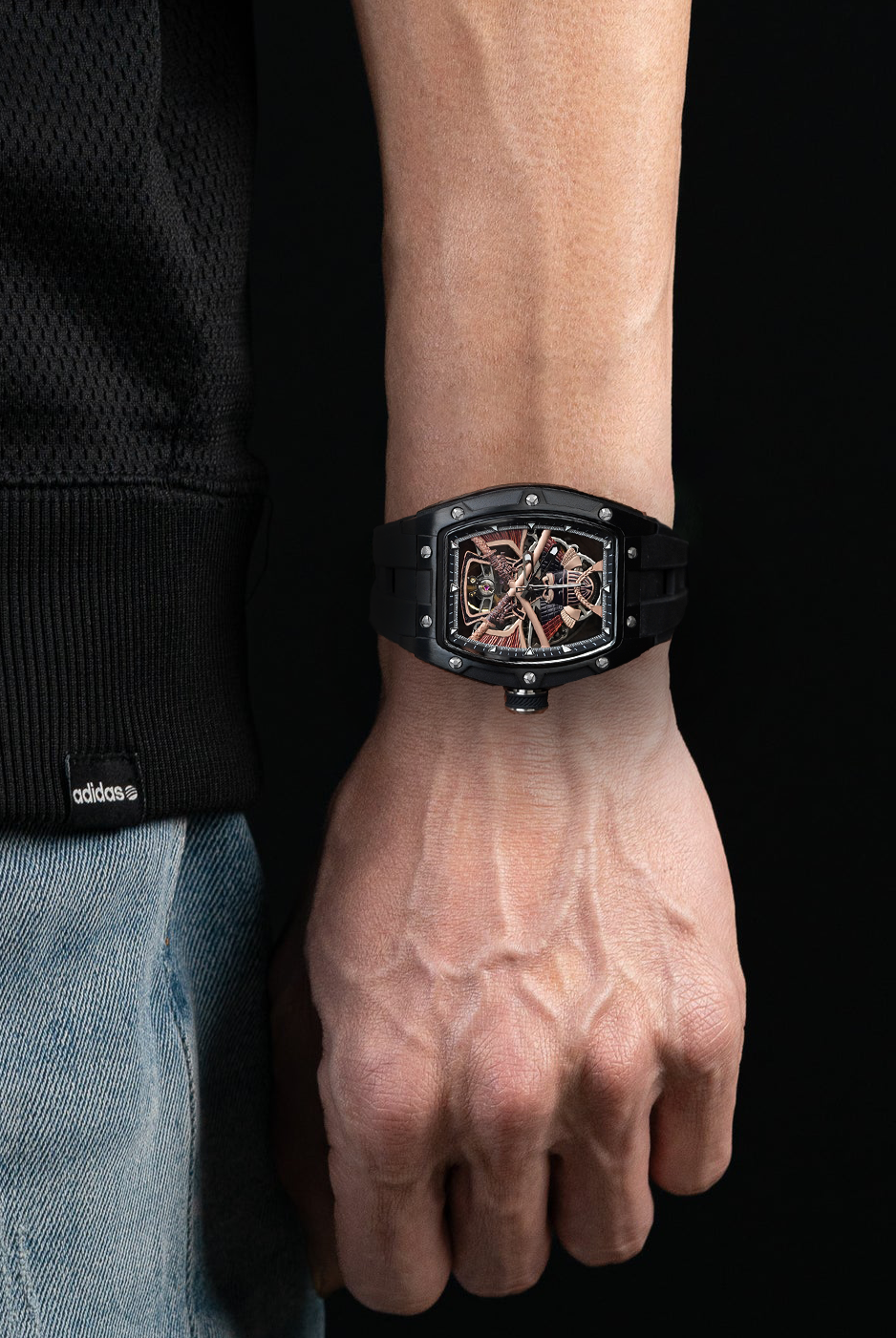 Person wearing a black watch on a dark background