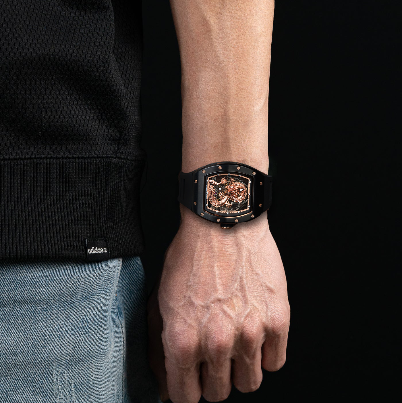 Person wearing a black watch with a detailed face on a black background