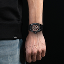 Person wearing a black watch on a dark background